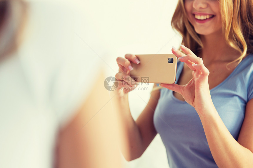 人技术亲密的快乐女人十几岁的女孩与智能手机拍照家特写少女用智能手机拍照图片