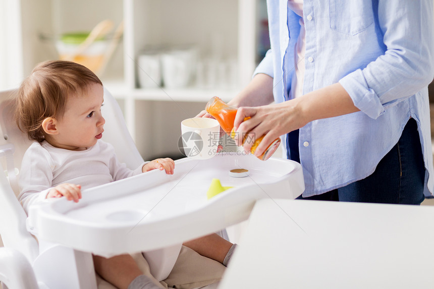 家庭,饮食,喂养人的小婴儿母亲家里厨房把天然胡萝卜汁璃瓶倒杯子婴儿母亲家里给杯子倒果汁图片