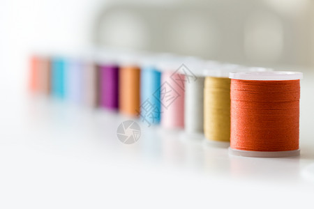 针线工艺缝纫裁剪桌子上排五颜六色的线轴桌子上排五颜六色的线轴背景图片