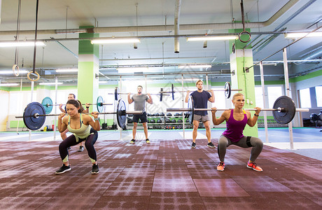 健身,运动,训练,锻炼生活方式的群杠铃的人健身房蹲下群人健身房用杠铃训练背景图片