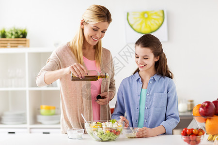 食物,健康饮食,家庭人的快乐的母亲女儿烹饪添加橄榄油蔬菜沙拉家庭厨房晚餐快乐的家庭烹饪沙拉家厨房快乐的家背景图片
