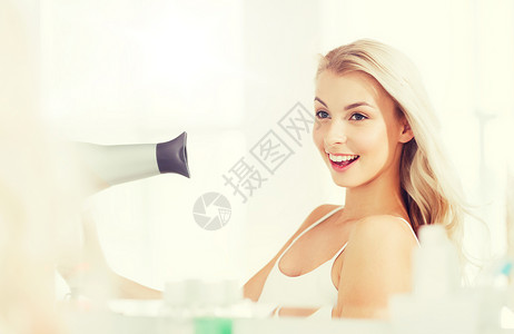 美丽,发型,早晨人的微笑的轻女人用扇子干她的头发,看着镜子家里的浴室快乐的轻女人浴室里用扇子烘干头发快图片