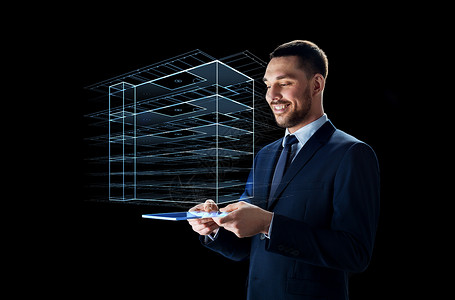 事实上商业,人未来的技术微笑的商人穿着西装与透明平板电脑虚拟建筑全息图黑色背景下工作拥平板电脑虚拟建筑的商人拥背景