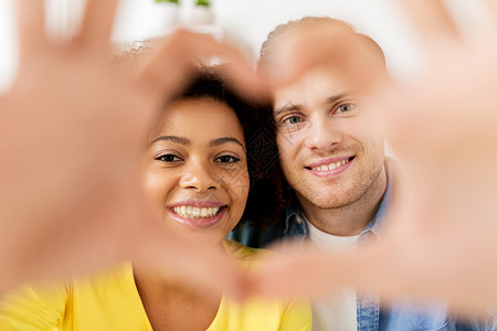情人节,爱人的快乐的多民族夫妇透过手指制成的心形幸福的夫妇穿过心形图片