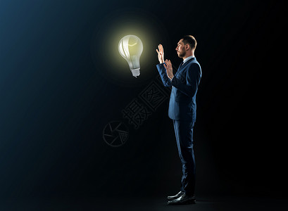 商业,人,创业理念,灵感办公室商人穿着黑色背景的灯泡黑色背景的灯泡的商人图片
