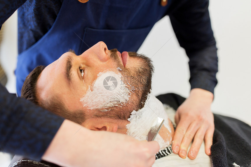 美容人的男人理发师的手与直剃刀剃须胡须理发店男人理发师留着笔直的剃刀胡须图片