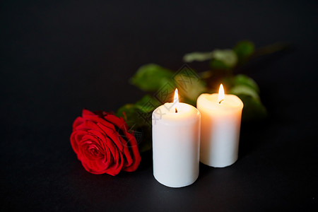 葬礼哀悼红色玫瑰燃烧蜡烛黑色背景红色玫瑰燃烧的蜡烛黑色的背景上背景图片