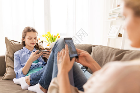 人,家庭技术快乐的女孩母亲家里智能手机家里智能手机的幸福家庭图片