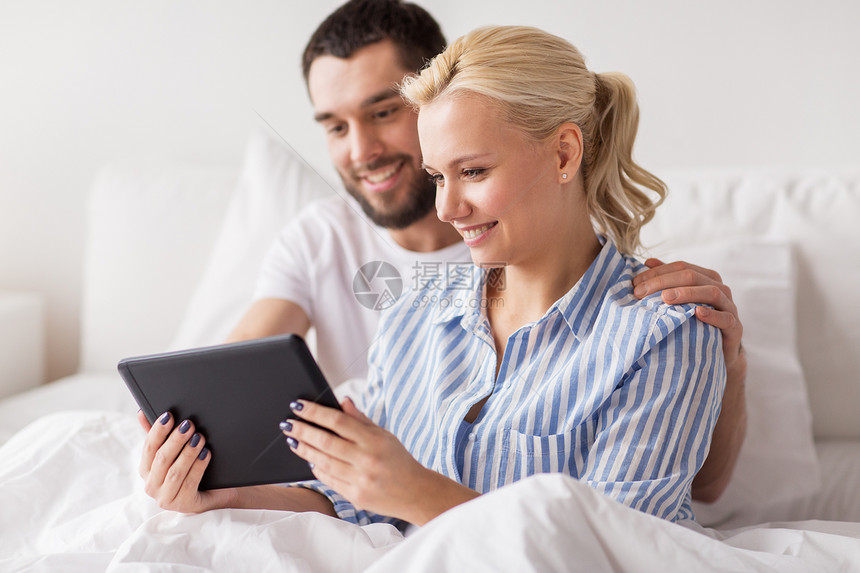 家庭,技术,互联网人的微笑幸福的夫妇与平板电脑电脑床上的家庭卧室微笑幸福的夫妇与平板电脑床上家图片