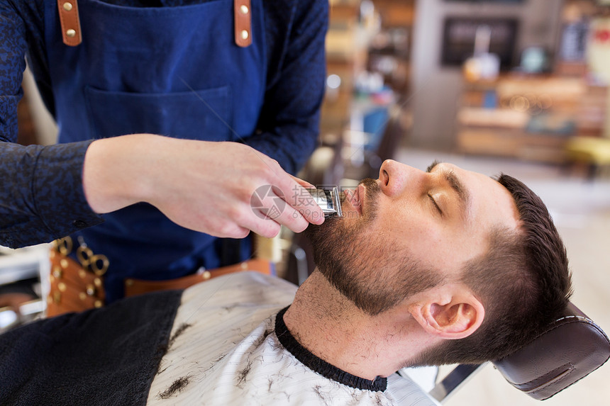 美容人的男人理发师的手与修剪剃须刀切割胡须理发店男人理发师沙龙剪胡子图片