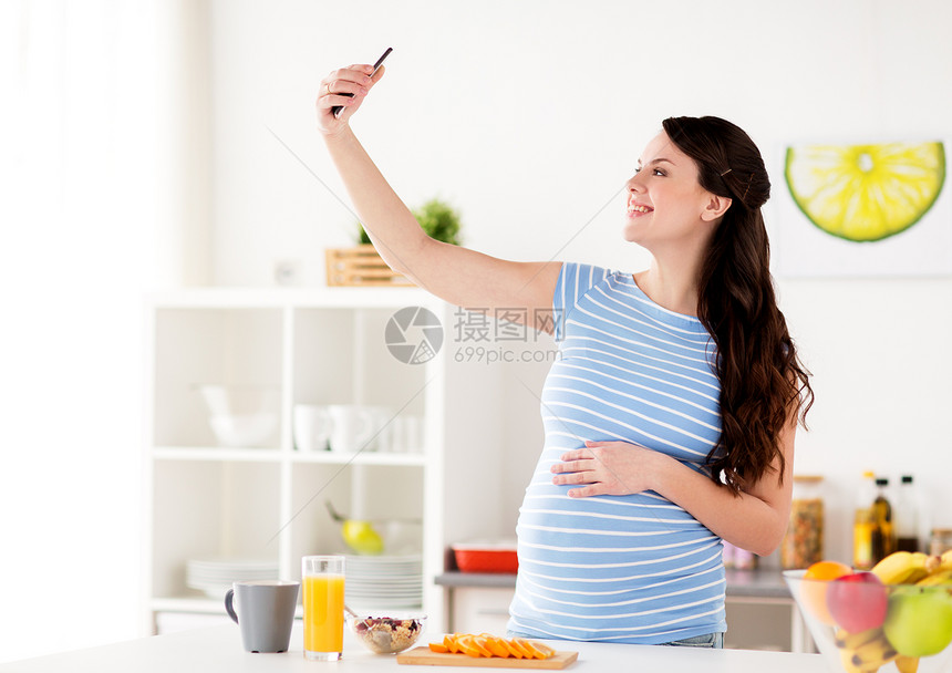 怀孕,人技术快乐的孕妇与智能手机自拍早餐家里厨房快乐的孕妇厨房用智能手机图片