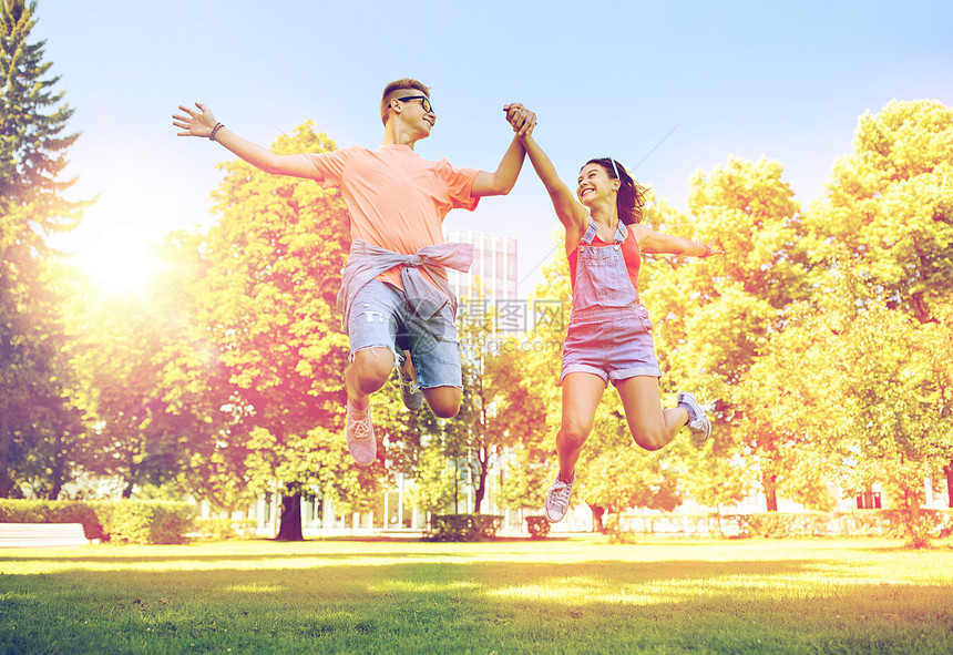 假期,爱人的快乐的微笑青少夫妇夏季公园跳跃快乐的十几岁的夫妇夏天的公园跳图片