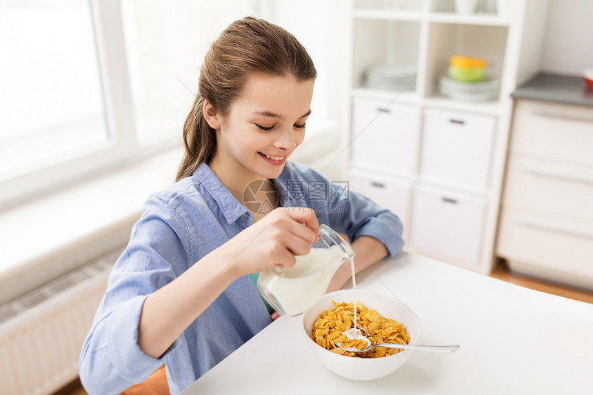 吃,早餐人们的快乐的女孩倒牛奶碗玉米片家里厨房快乐的女孩家里的厨房吃早餐图片