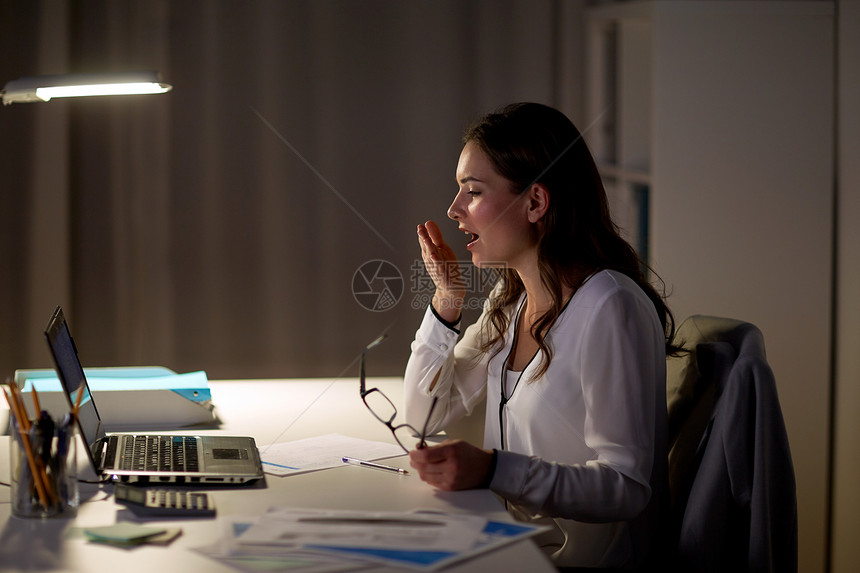 商务,过度工作,截止日期人的疲惫的女人戴着眼镜笔记本电脑夜间办公室打哈欠疲惫的女人带着笔记本夜间办公室打哈欠图片