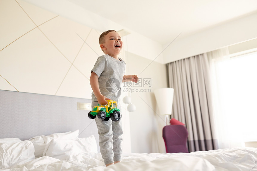 人,童早晨的快乐的小男孩与玩具汽车家里酒店床上快乐的小男孩,玩具车家里酒店床上图片