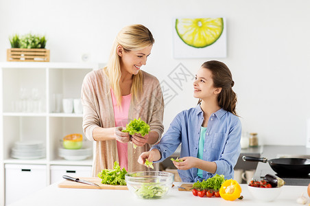 说话的女孩母亲和女儿在厨房烹饪沙拉背景