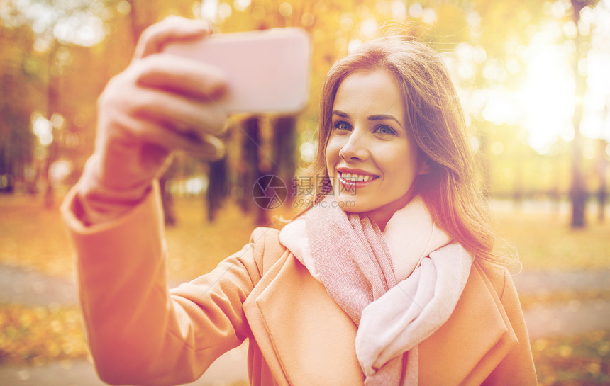 季节,技术人的美丽的轻快乐的女人自拍与智能手机秋季公园女人秋天公园用智能手机自拍图片