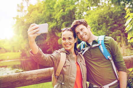 旅行,徒步旅行,背包,旅游人的微笑夫妇与背包采取自拍智能手机自然界夫妇用智能手机自拍背包背景图片