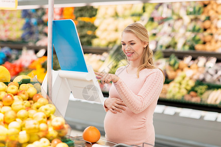 销售,购物,食物,怀孕人们的快乐的孕妇称重柚子杂货店超市孕妇杂货店里用柚子秤背景图片