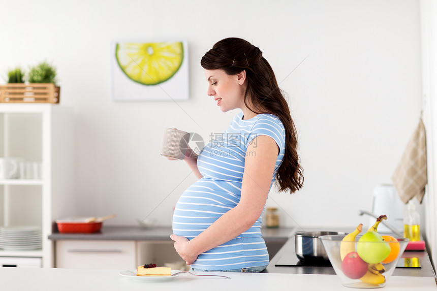 怀孕,人们期望的快乐的孕妇家里厨房喝杯茶块蛋糕快乐的孕妇家里着杯子蛋糕图片