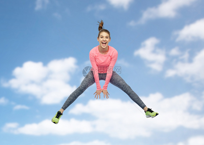 运动,健身,运动人的快乐的微笑轻女人蓝天云层背景上跳跃快乐微笑运动的轻女人天空中跳跃图片
