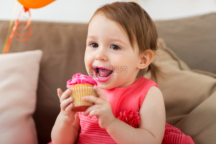 童,人庆祝快乐的女婴家里的生日聚会上吃纸杯蛋糕生日派上快乐的女婴吃纸杯蛋糕图片
