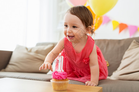 童,人庆祝快乐的女婴与纸杯蛋糕生日聚会家里带生日蛋糕的女婴家聚会图片