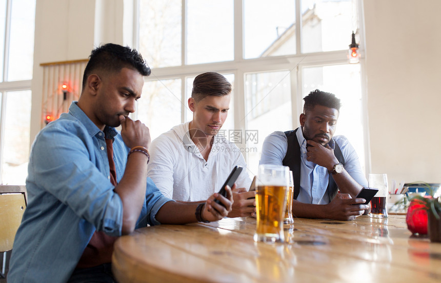 人们,男友谊技术朋友与智能手机酒吧酒吧喝啤酒智能手机的男朋友酒吧喝啤酒图片