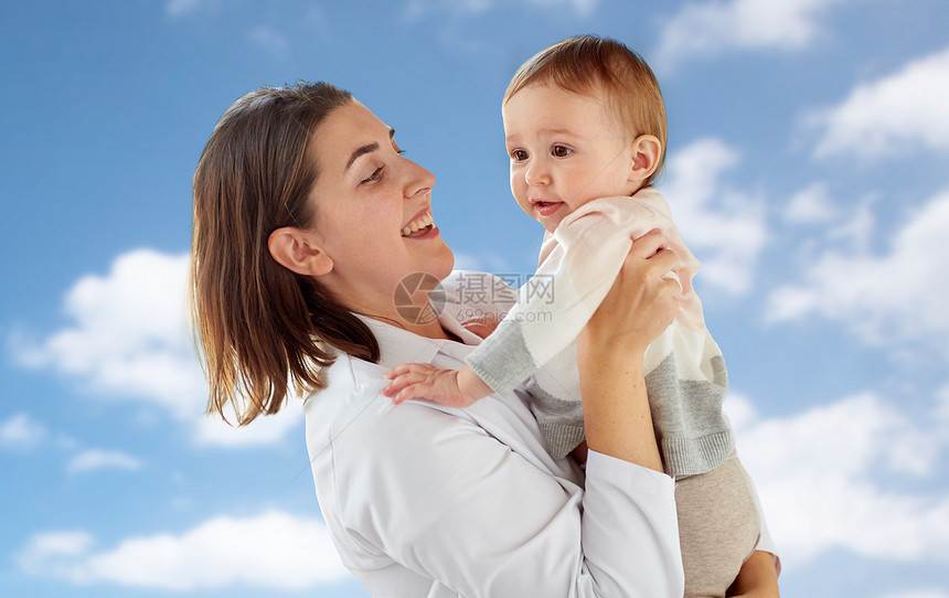 医学,医疗,儿科人的快乐的女医生儿科医生抱着婴儿蓝天背景快乐的医生儿科医生带着天空图片