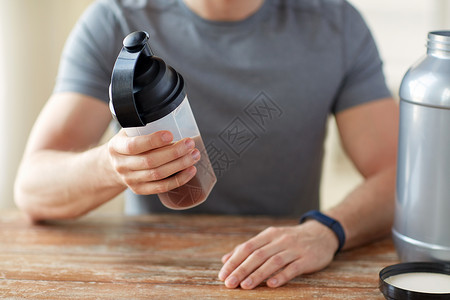 与声俱来运动,健康的生活方式人们的接近男人穿着健身追踪器与罐子瓶子准备蛋白质奶昔用蛋白瓶罐子把人关来背景