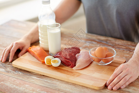运动营养,健康饮食人的密切的男手与富含蛋白质的食物木制切割板把食物中富含蛋白质的人关来背景