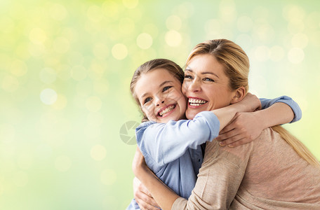 人家庭的快乐的微笑女孩与母亲拥抱节日的灯光背景快乐的女孩母亲拥抱灯光背景图片