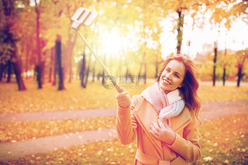 季节,技术人的美丽的轻快乐的女人秋天公园用智能手机自拍棒拍照女人秋天公园用智能手机自拍图片
