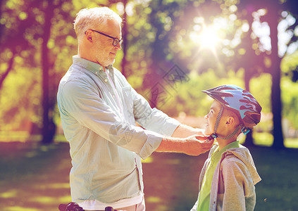 家庭,世代,安全人的快乐的祖父帮助男孩夏季公园的自行车头盔老人公园帮男孩带自行车头盔背景图片