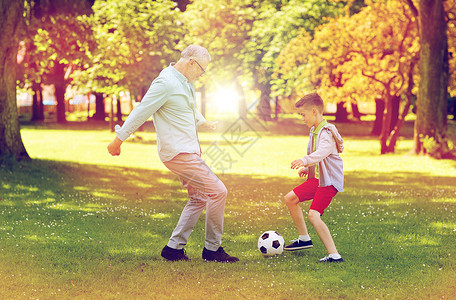 玩足球老人家庭,世代,游戏,体育人的快乐的祖父孙子夏天的公园踢足球老人男孩夏天的公园踢足球背景