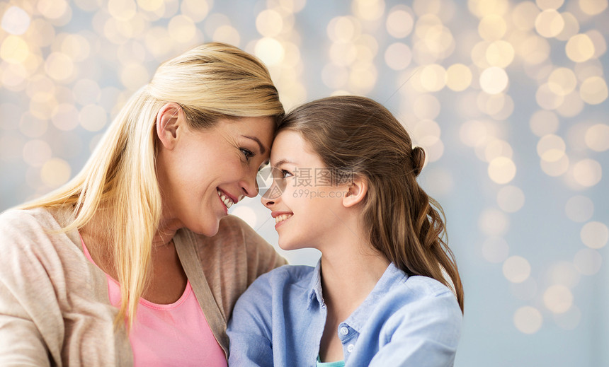人家庭的快乐的微笑女孩与母亲拥抱节日的灯光背景快乐的女孩母亲拥抱灯光图片