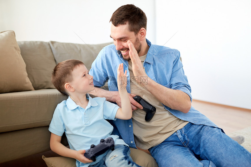 家庭,父亲人的快乐的父亲小儿子玩电子游戏家里高中五父子游戏玩家击掌图片