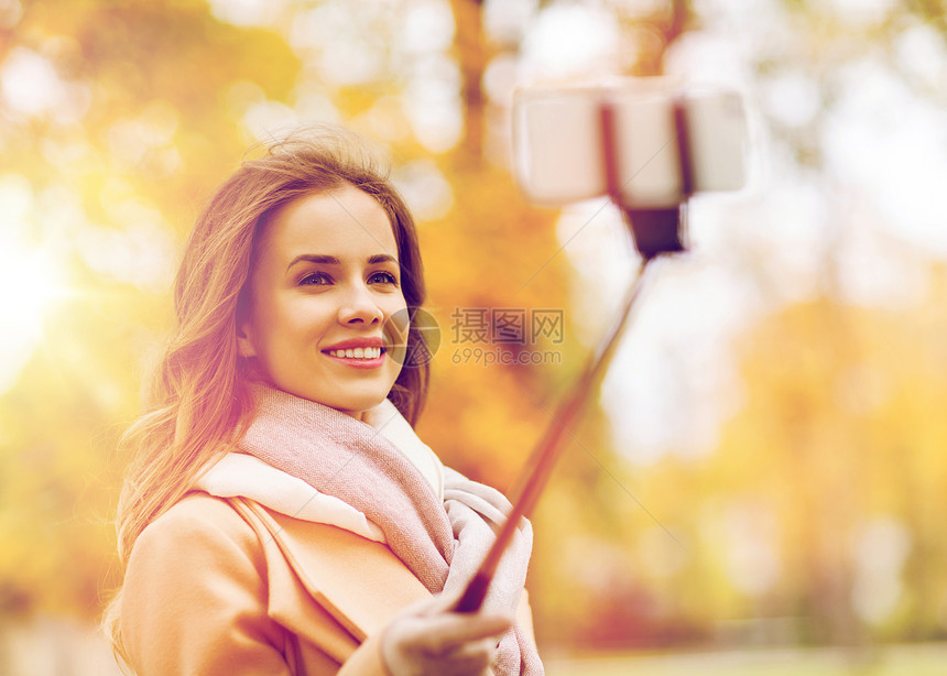 季节,技术人的美丽的轻快乐的女人秋天公园用智能手机自拍棒拍照女人秋天公园用智能手机自拍图片