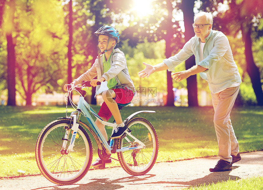 家庭,世代,安全人的快乐祖父教男孩如何骑自行车夏季公园祖父男孩夏季公园骑自行车图片