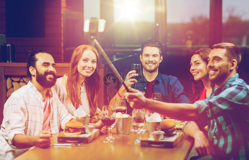 休闲,技术,友谊,人假日的快乐的朋友餐厅用智能手机自拍棒吃饭拍照朋友们餐厅用智能手机自拍图片