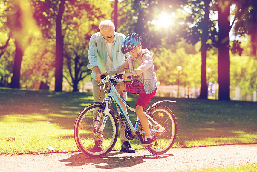 家庭,世代,安全人的快乐祖父教男孩如何骑自行车夏季公园祖父男孩夏季公园骑自行车图片
