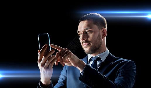 账期商业,增强现实未来的技术适合与透明智能手机黑色背景下工作的商人拥透明智能手机的商人设计图片