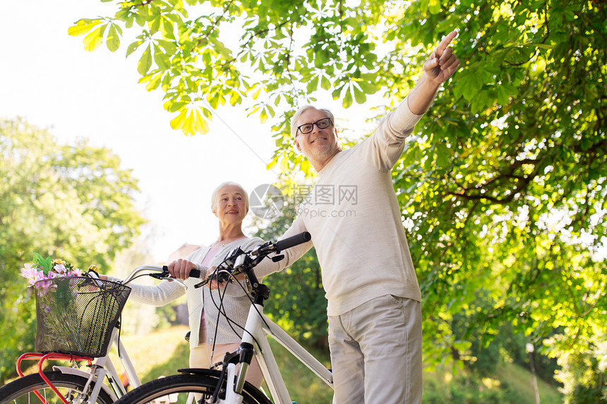 老人,人生活方式的快乐的老夫妇步行与固定自行车夏季城市公园快乐的老夫妇夏季公园骑自行车图片