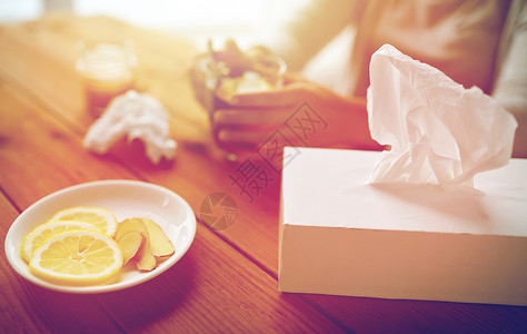健康,传统医学民族科学生病的女人喝茶与柠檬,蜂蜜生姜纸巾盒木桌上生病的女人喝柠檬生姜的茶背景图片
