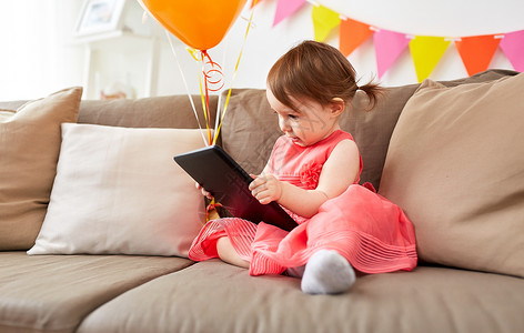 宝贝生日童,假期人的快乐的女婴与平板电脑气球生日聚会家里家里平板电脑的女婴生日聚会上背景