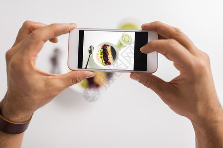 健康的饮食,人技术的用智能手机拍摄早餐男人用智能手机拍摄健康早餐图片