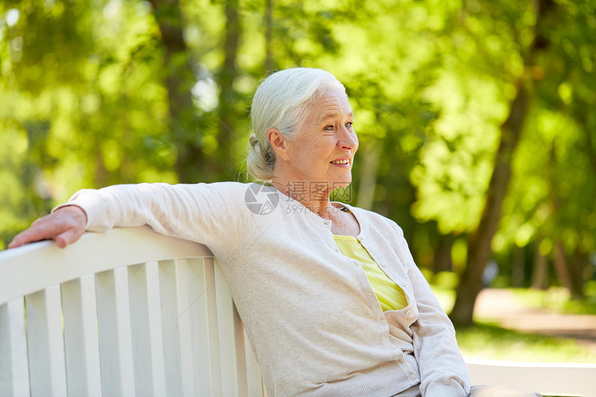 老,退休人们的快乐的老妇女戴着眼镜,坐夏季公园的长凳上快乐的高级女人坐夏天公园的长凳上图片