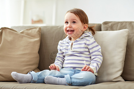 童,情感人的快乐的微笑女婴坐家里的沙发上快乐微笑的女婴坐家里的沙发上图片