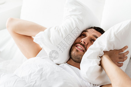 人们,睡觉时间休息的男人躺床上,枕头家里被噪音所困扰男人躺床上,枕头上噪音图片