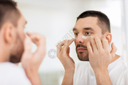 美容,皮肤护理人的轻人应用保湿剂镜子家庭浴室轻人浴室用奶油洗脸图片